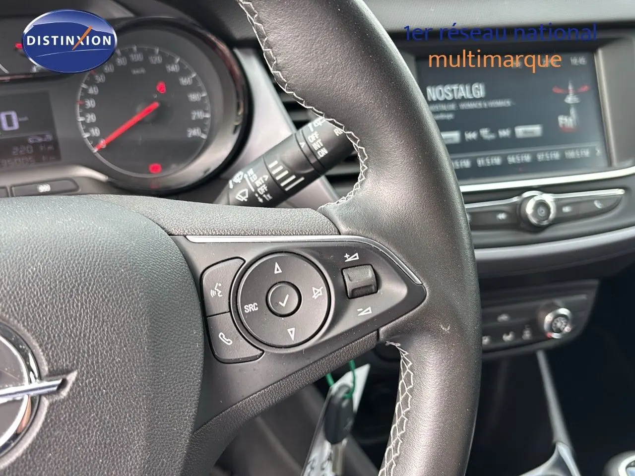 Gros plan sur le volant et la console centrale d'un Opel Crossland X gris Pierre de Lune, mettant en valeur les commandes au volant et l'écran multimédia.