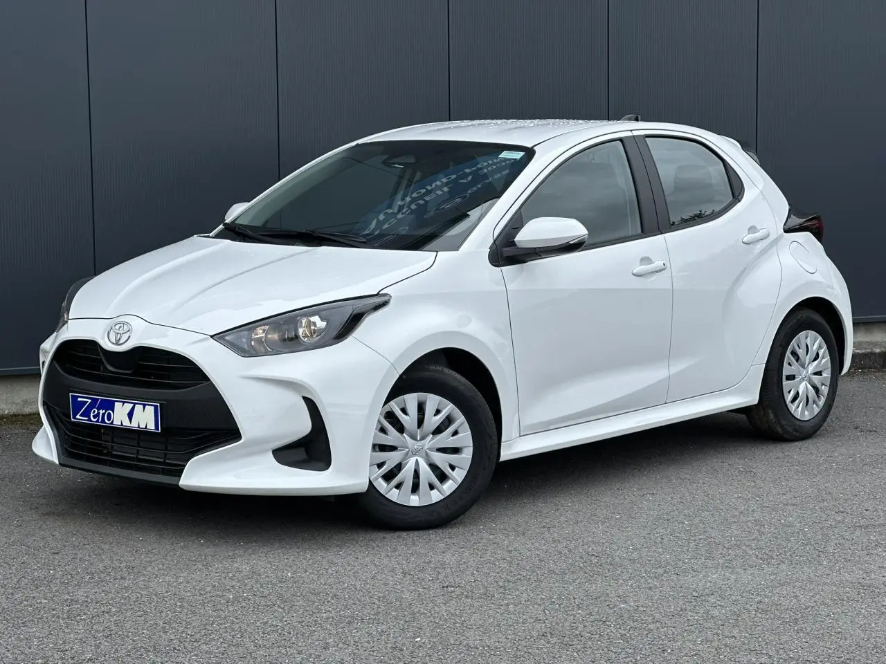 Toyota Yaris hybride blanc pur vue 3/4 avant droit avec calandre noire et jantes acier à enjoliveurs.