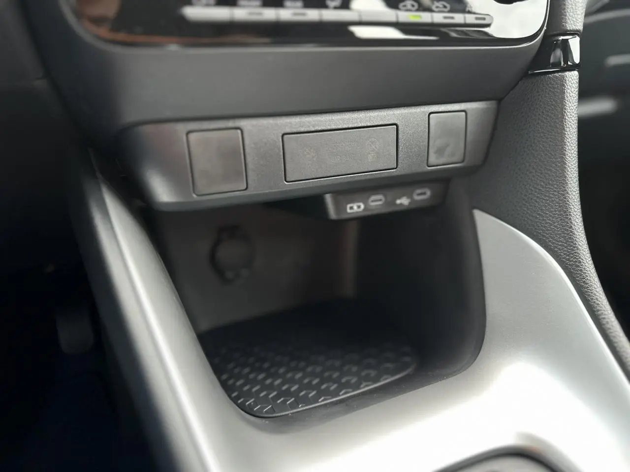 Gros plan sur la console centrale de la Toyota Yaris Hybride 2025 montrant les ports USB-C et un rangement noir mat.
