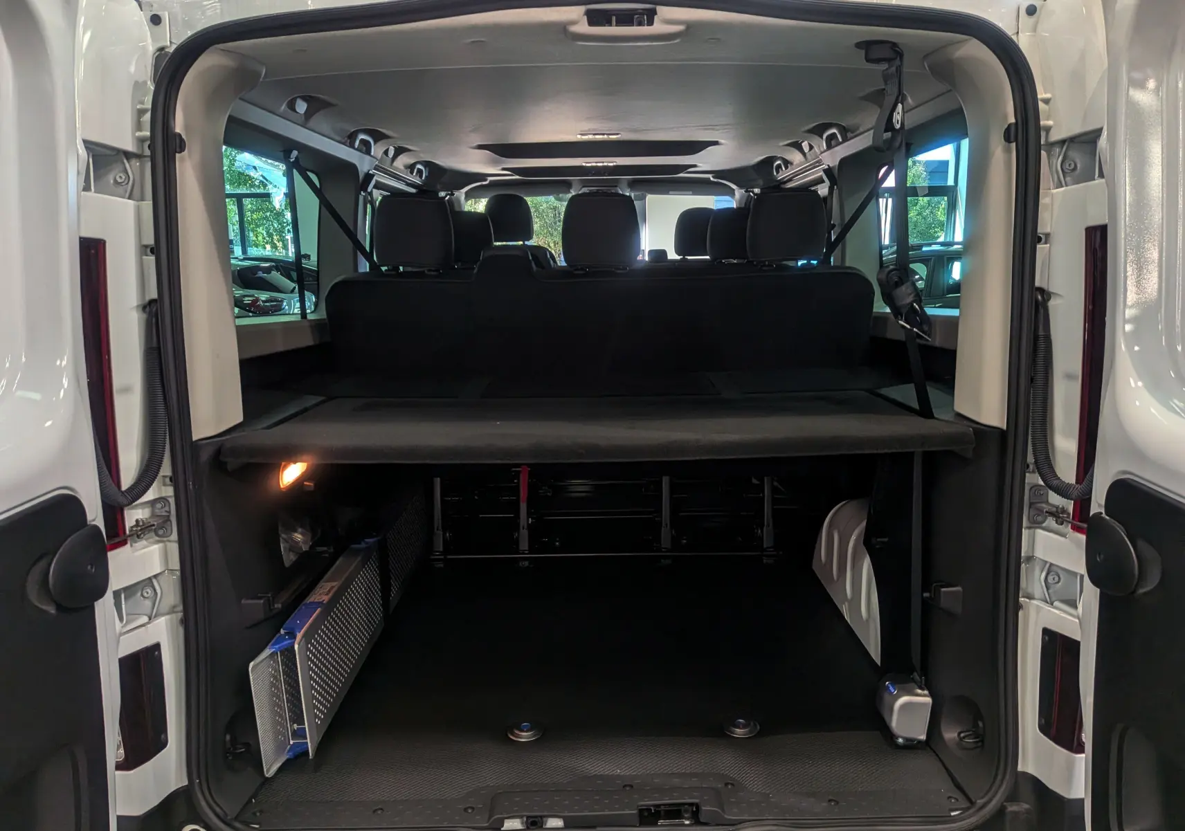 Vue arrière ouverte du Renault Trafic Combi blanc glacier montrant l'espace de chargement et les sièges arrière noirs.
