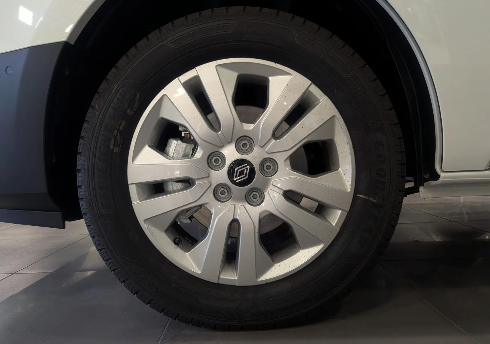 Gros plan sur la roue avant droite du Renault Trafic Combi blanc Glacier avec jante alliage et pneu Goodyear.