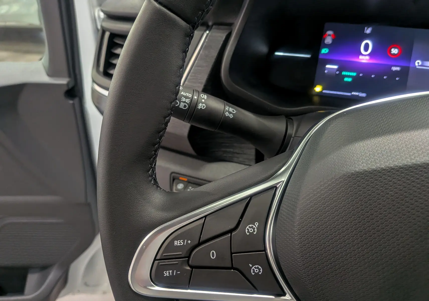 Gros plan sur le volant noir du Renault Trafic Combi blanc glacier avec tableau de bord digital allumé.