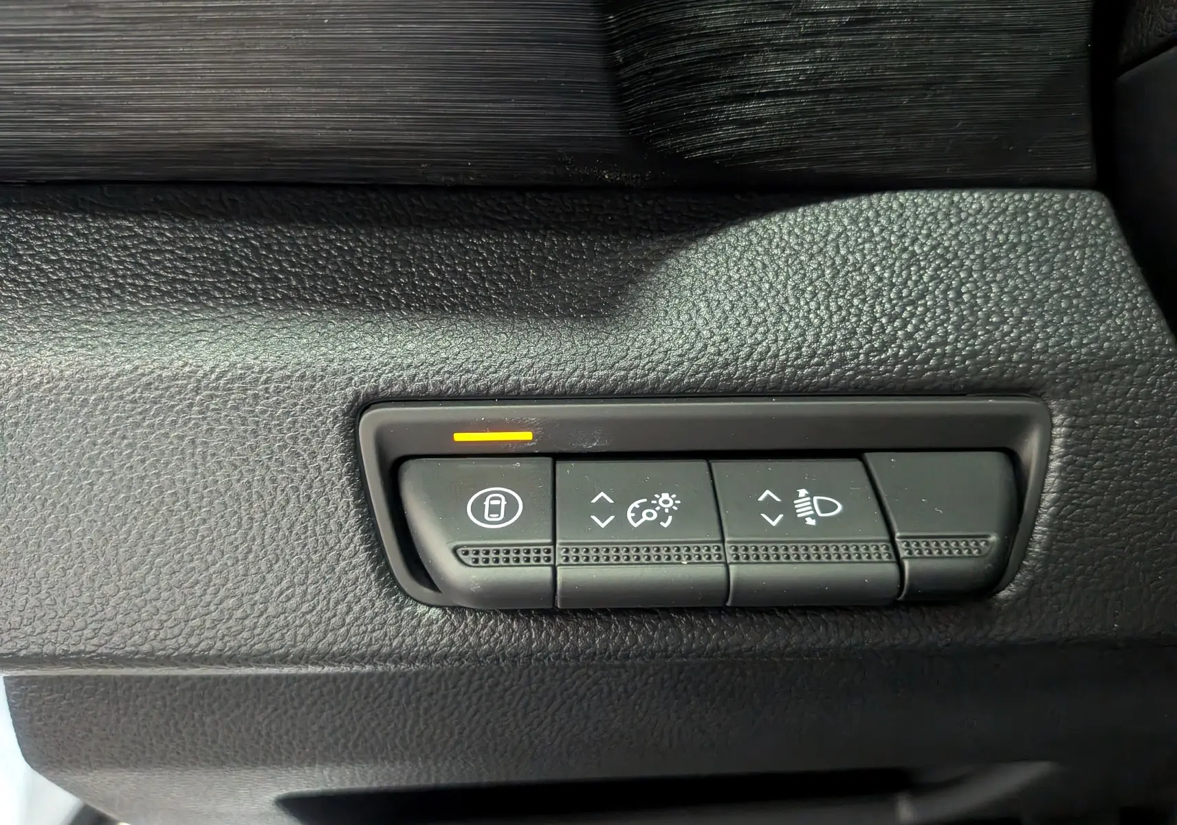 Gros plan sur les commandes de réglage des phares et verrouillage dans l'habitacle noir du Renault Trafic Combi blanc.