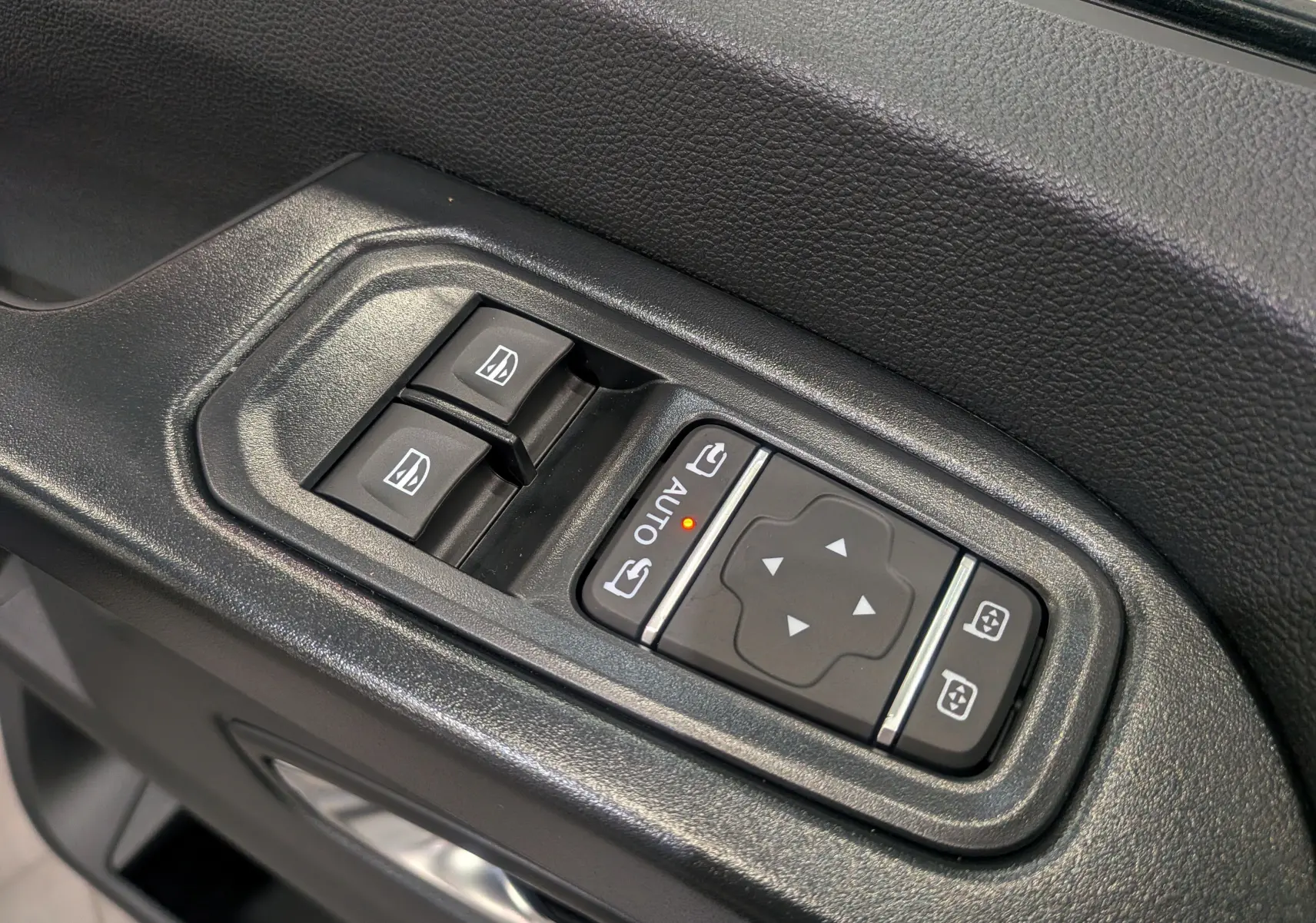 Gros plan sur les commandes électriques des vitres et rétroviseurs côté conducteur du Renault Trafic Combi blanc Glacier 2025.