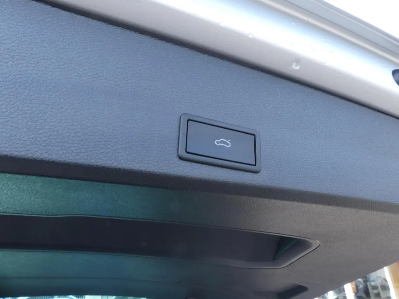 Bouton d'ouverture électrique du hayon sur la face intérieure du coffre d'un SEAT Ateca gris clair 2023.