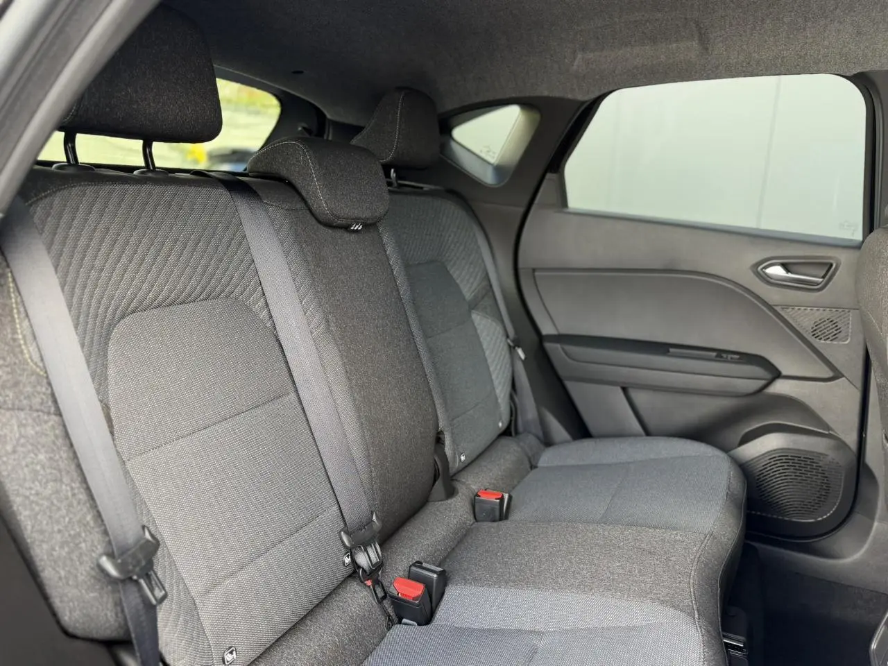 Vue intérieure côté droit des sièges arrière gris foncé du Renault Captur 2026 avec ceintures de sécurité et appuie-têtes.