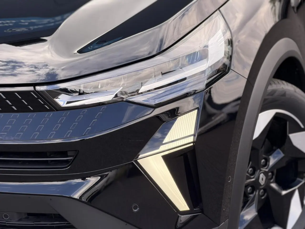 Gros plan sur l'avant droit noir étoilé du Renault Captur 2026, mettant en valeur le phare LED et la jante aluminium.