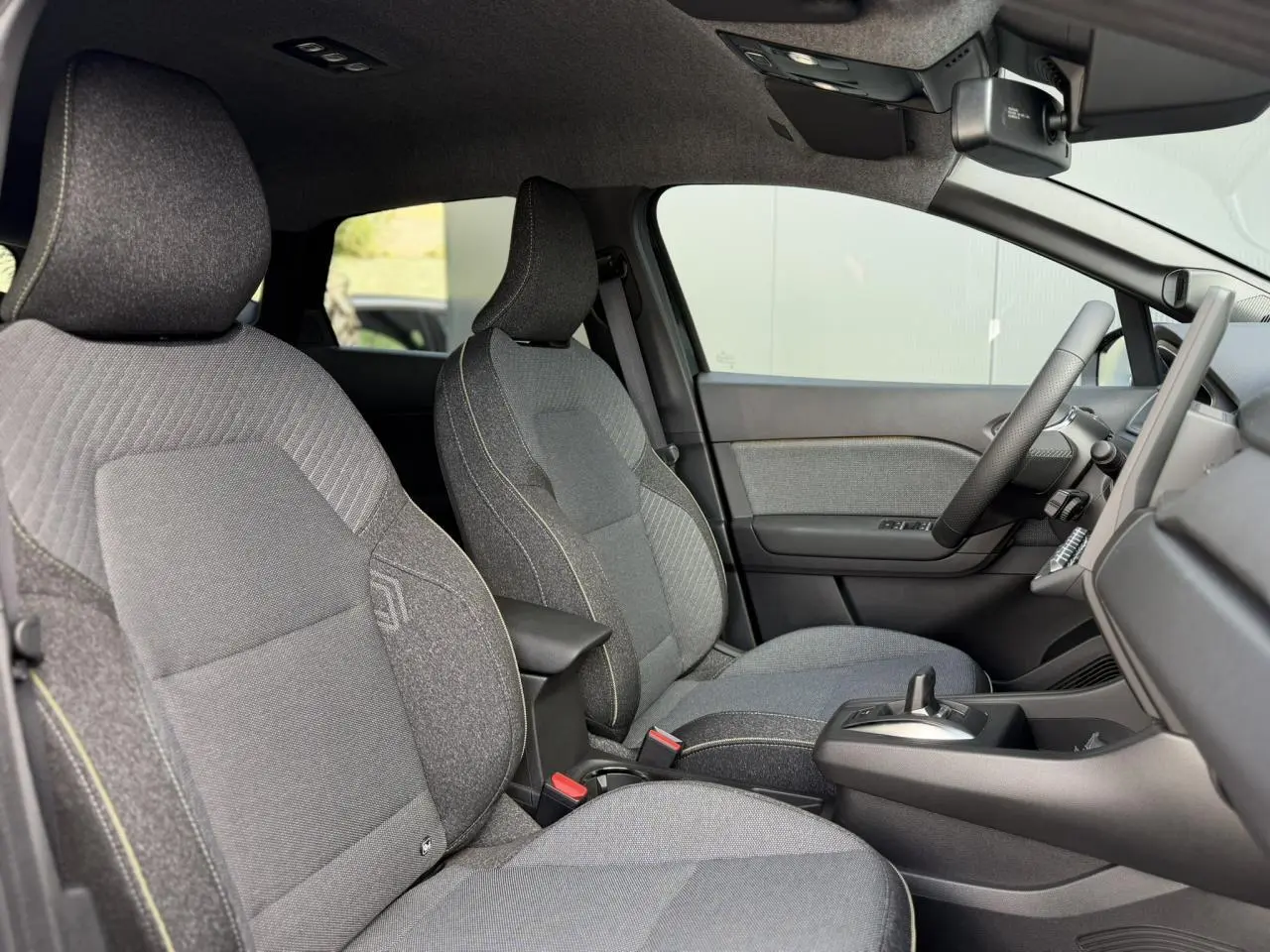 Vue intérieure côté droit du Renault Captur 2026, sièges tissu gris avec coutures jaunes et console centrale noire.