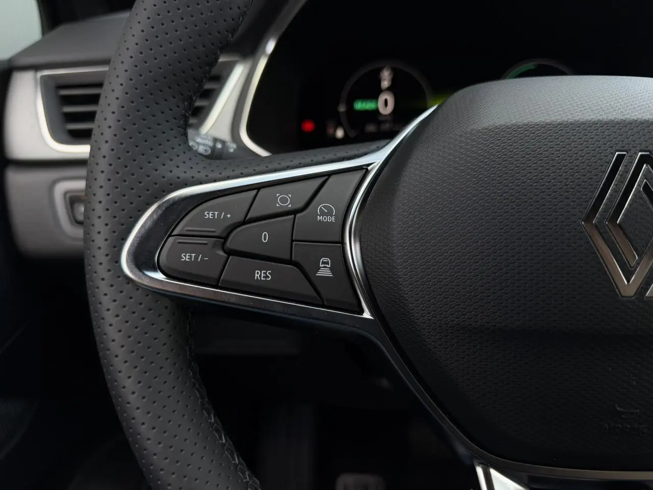 Gros plan sur le côté gauche du volant noir perforé du Renault Captur 2026 avec commandes intégrées et logo Renault central.