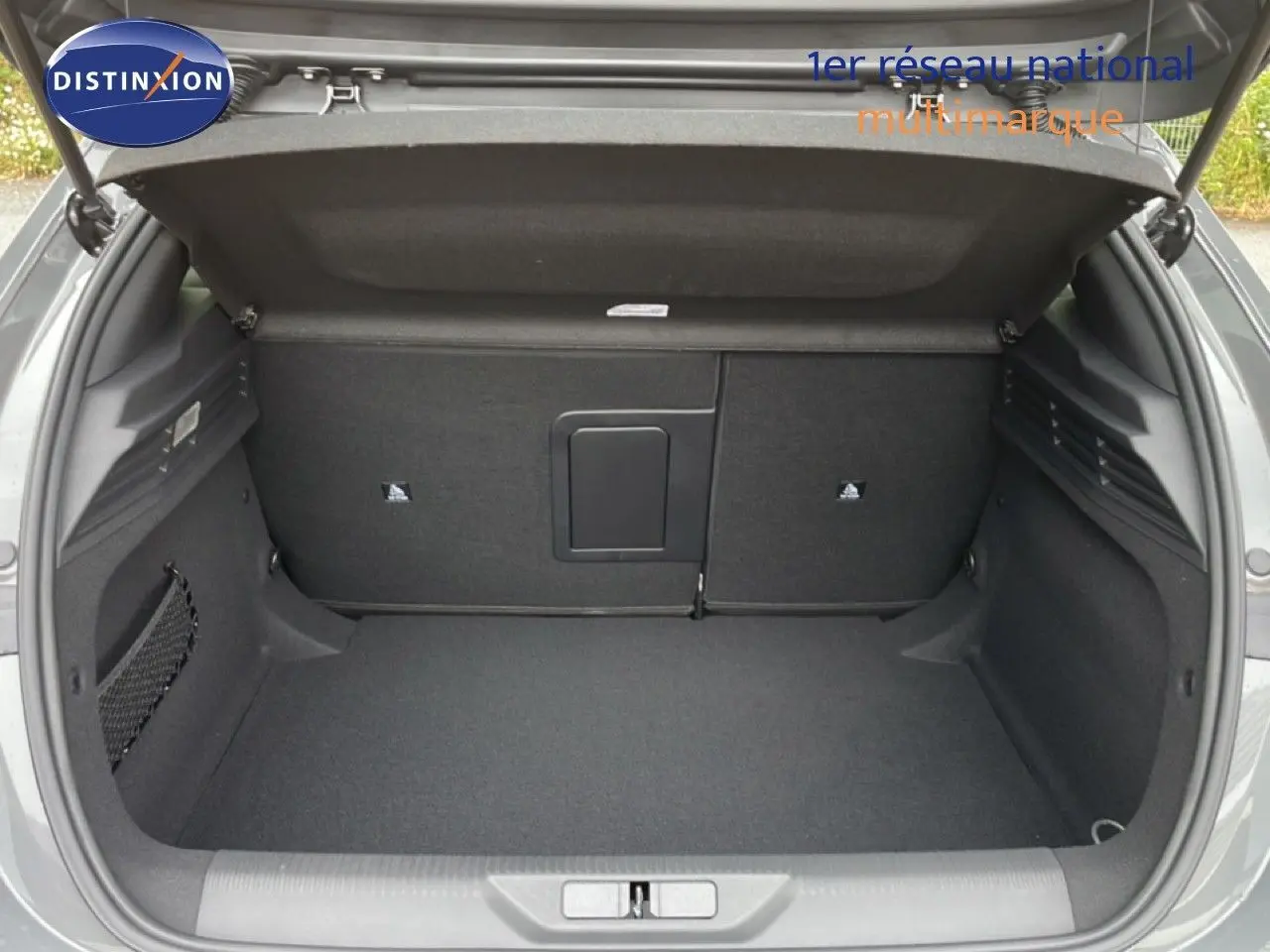 Coffre ouvert vu de l'arrière d'une Peugeot 308 gris selenium métal, espace de chargement propre et spacieux.