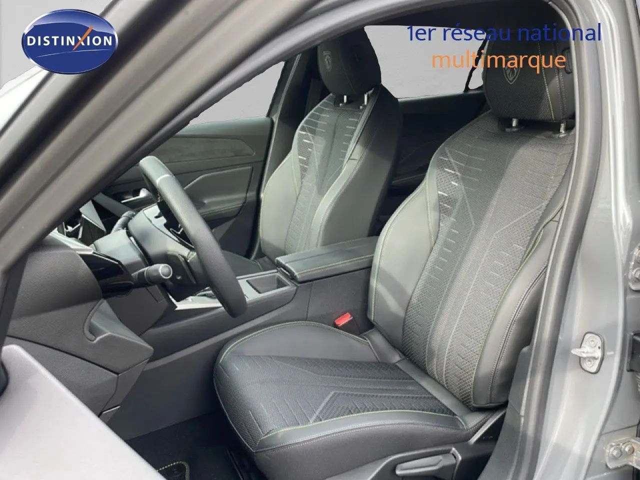 Vue intérieure côté conducteur de la Peugeot 308 gris selenium, mettant en valeur les sièges en tissu et cuir avec surpiqûres contrastées.