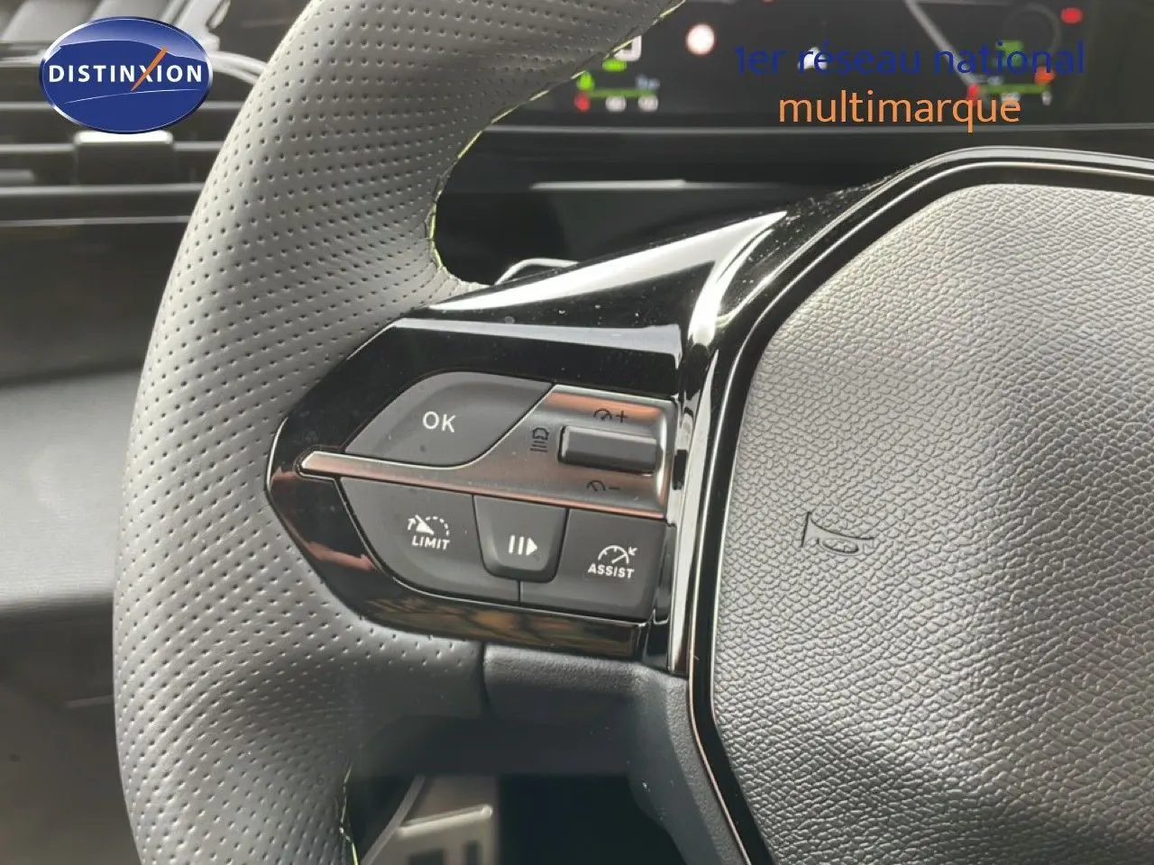 Gros plan sur le volant gris perforé avec commandes intégrées du Peugeot 308 gris selenium metal, version hybride 2026.