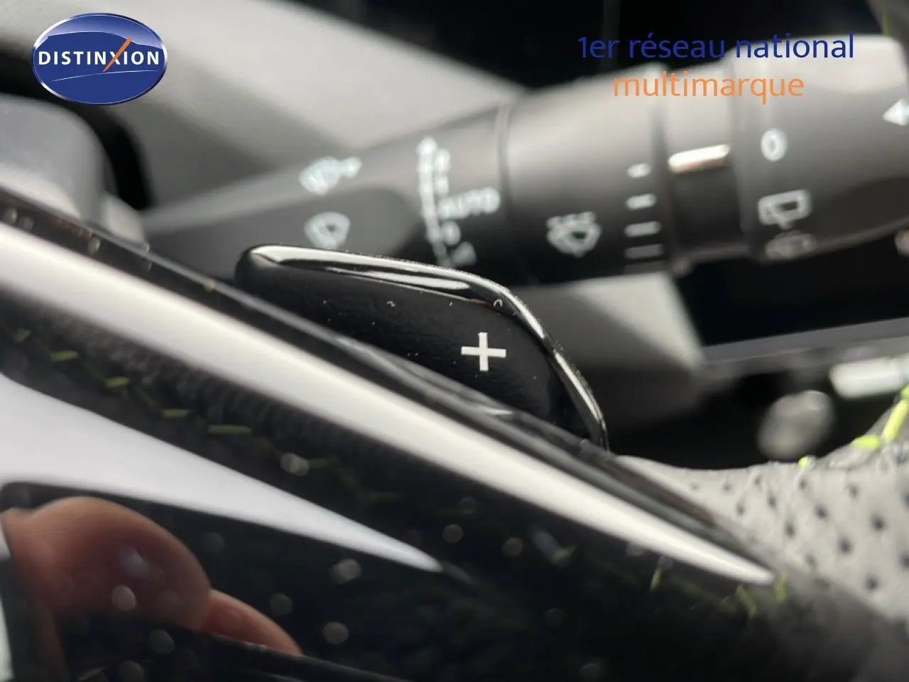 Gros plan sur la palette de changement de vitesse "+" au volant d'une Peugeot 308 gris selenium hybride 2026.