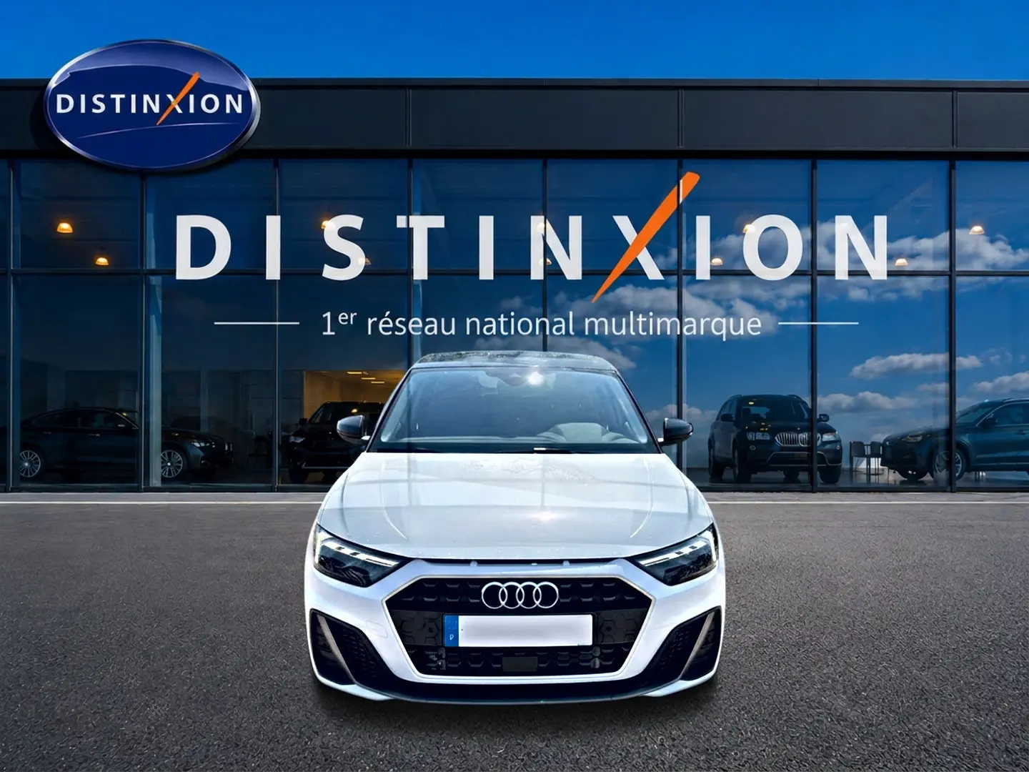 Audi A1 Sportback blanc et noir vue de face, avec calandre noire et logo Audi, devant une vitrine Distinxion.