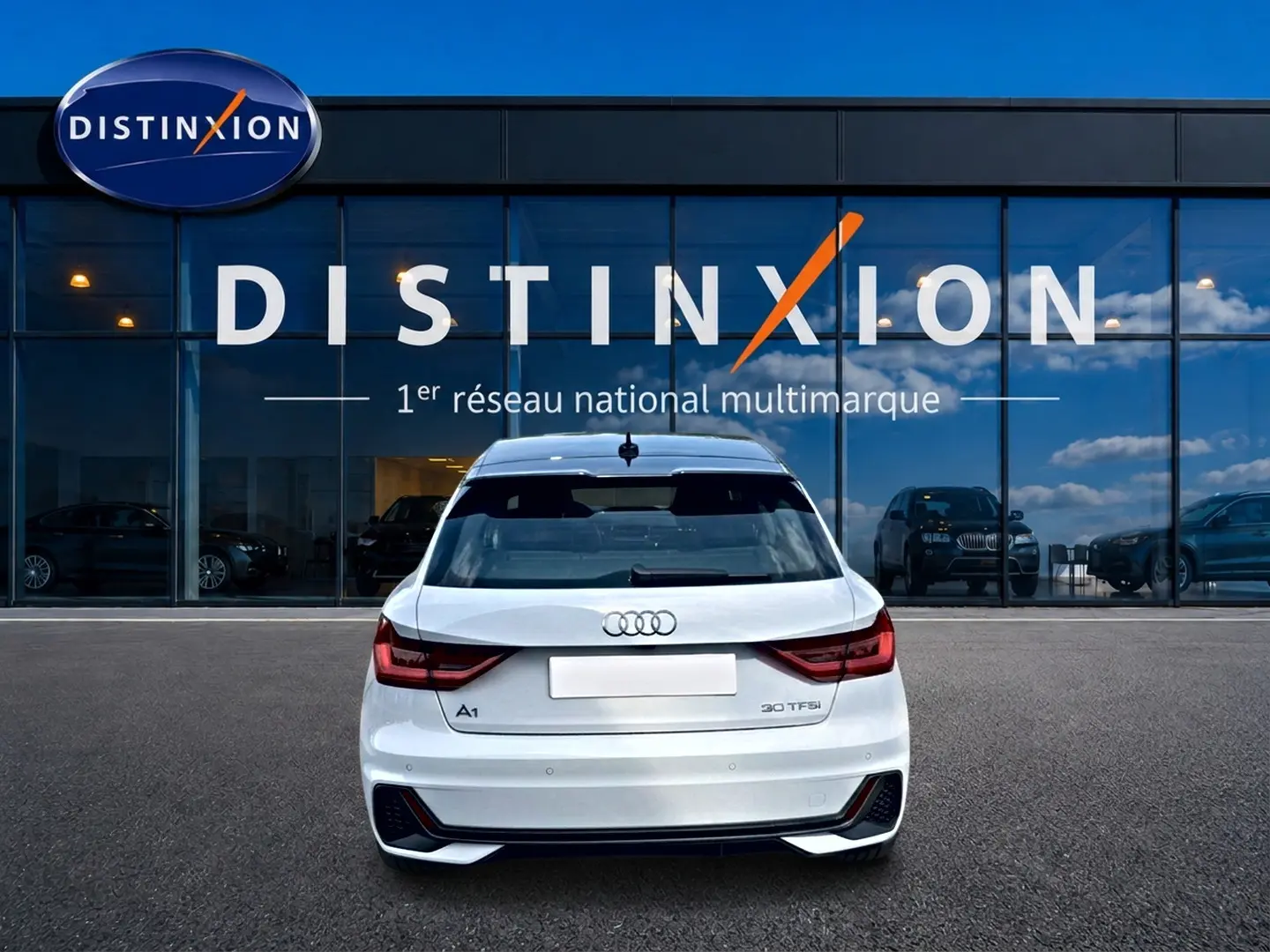 Vue arrière d'une Audi A1 Sportback 30 TFSI blanche avec détails noirs, stationnée devant une vitrine Distinxion.