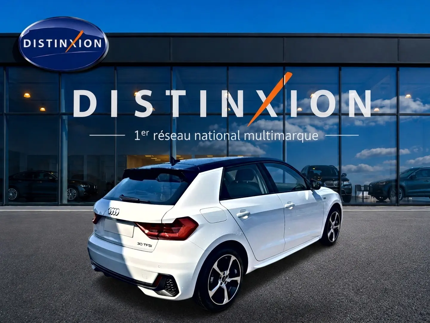 Audi A1 Sportback blanc et noir vue 3/4 arrière droit avec jantes alu et becquet arrière, devant vitrine Distinxion.