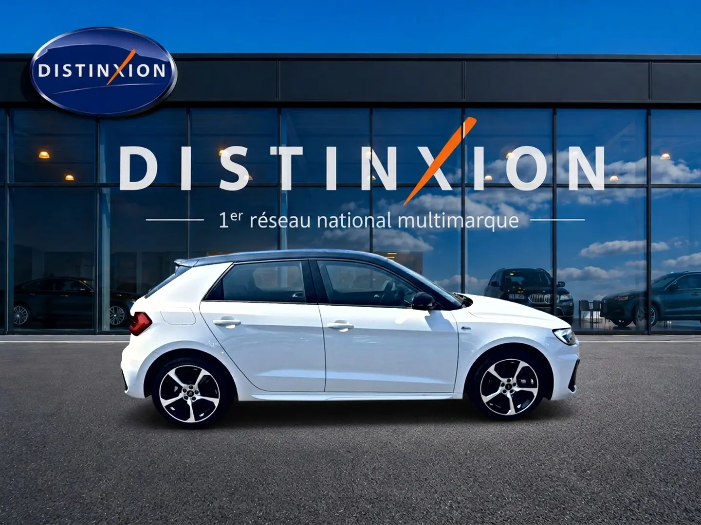 Audi A1 Sportback blanc et noir vue de profil côté gauche, avec jantes alu et toit noir devant vitrine Distinxion.
