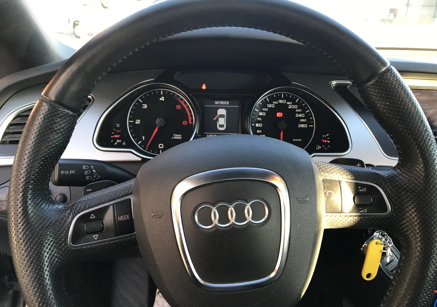Vue rapprochée du volant en cuir noir d'une Audi A5 Coupé gris dauphin avec tableau de bord et compteurs visibles.