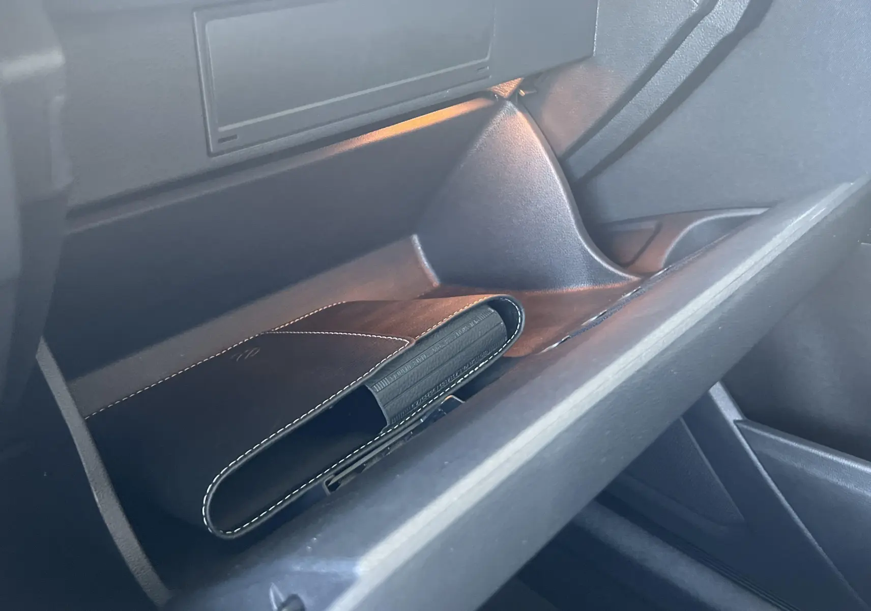 Gant de poche noir avec coutures blanches dans la boîte à gants côté passager du Volkswagen T-Roc 2024.