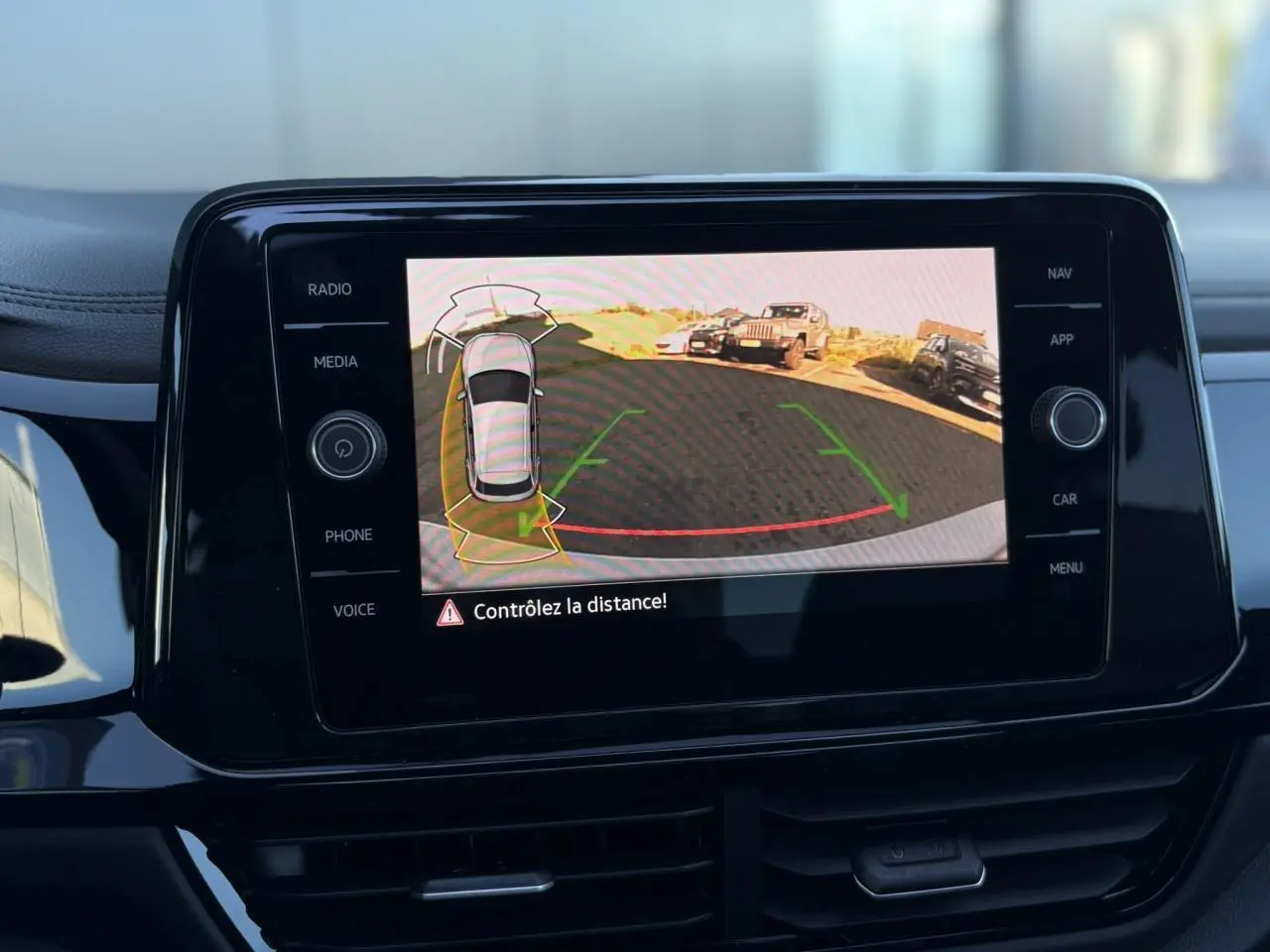 Écran central affichant la caméra de recul et l'alerte de distance du Volkswagen T-Roc 2.0 TDI gris Pyrite.