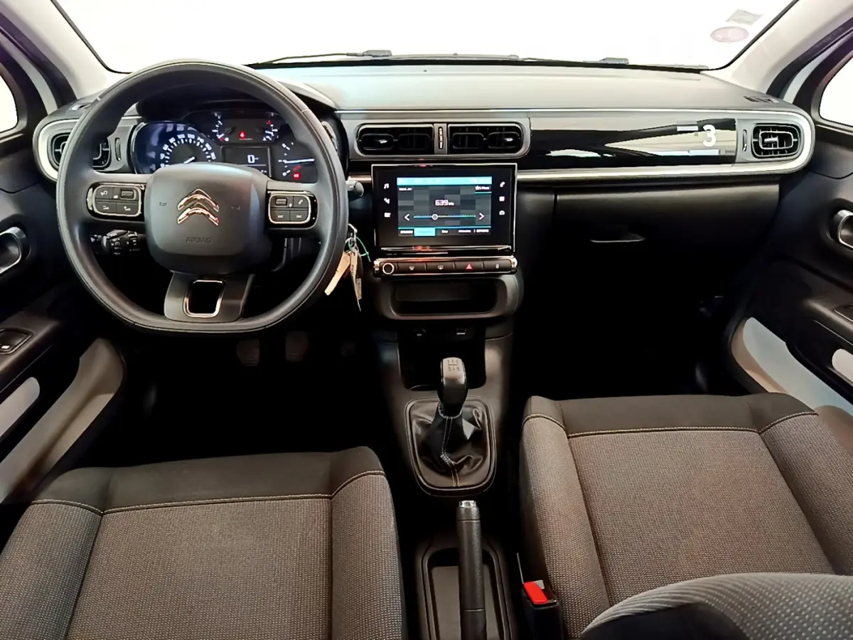 Intérieur de la Citroën C3 PureTech 82 blanc, vue frontale du tableau de bord avec écran tactile et volant multifonctions.