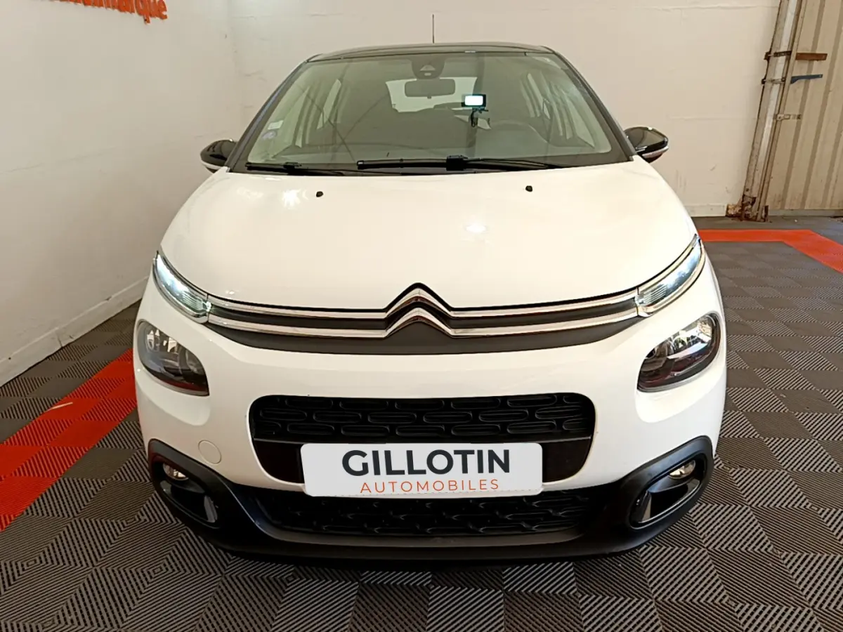 Vue frontale d'une Citroën C3 blanche de 2019 avec calandre noire et feux LED distinctifs dans un showroom.