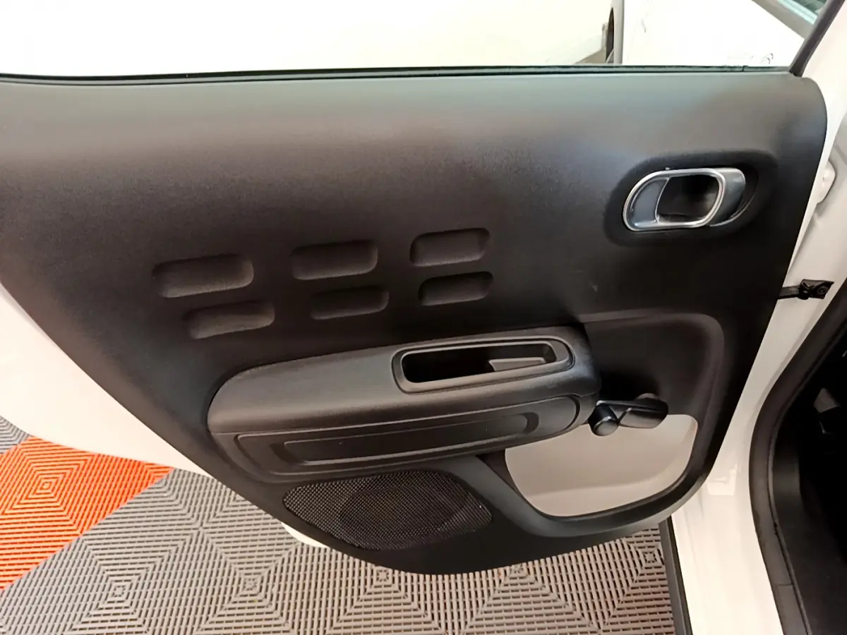 Vue rapprochée de la porte avant gauche noire et blanche d'une Citroën C3 PureTech 2019 avec poignée chromée.