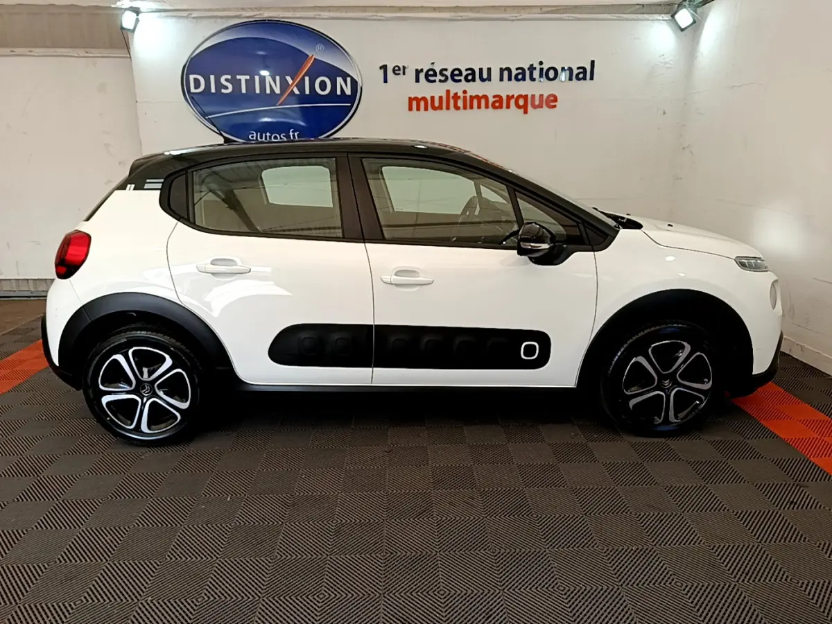 Profil droit d'une Citroën C3 PureTech 82 blanc avec toit noir et protections latérales noires distinctives.