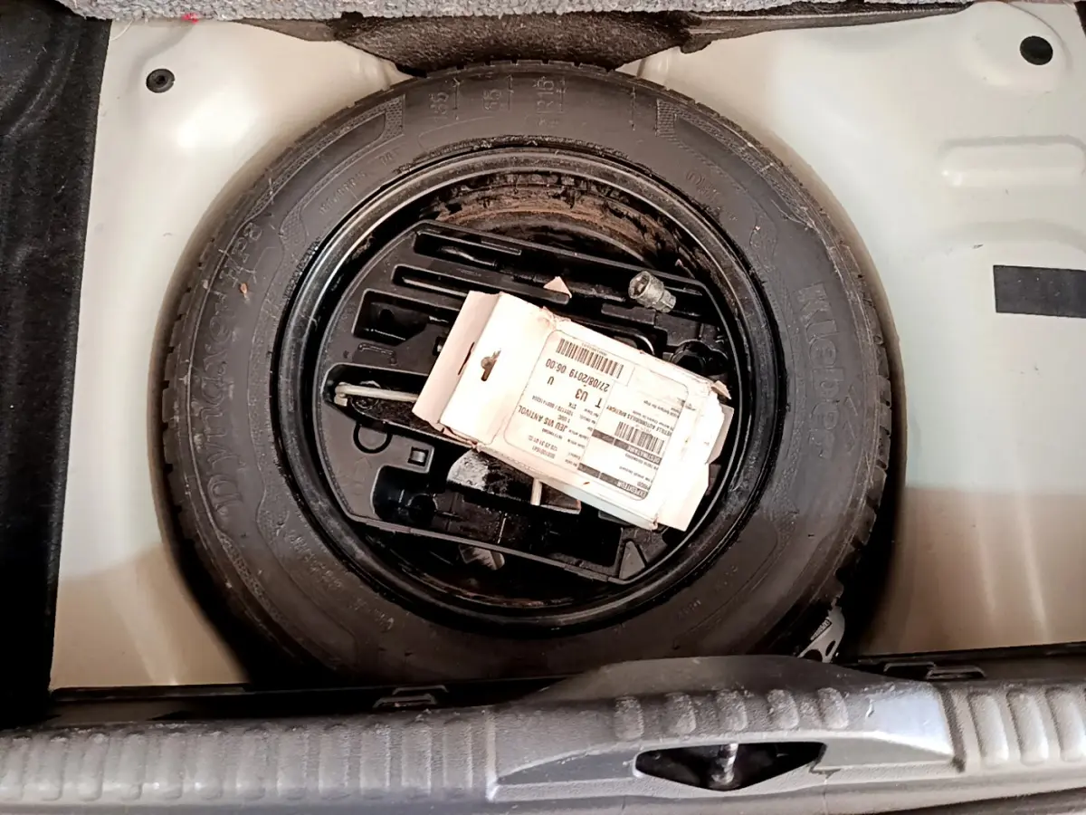 Gros plan sur la roue de secours noire dans le coffre blanc d'une Citroën C3 PureTech 82 S&S BVM Graphic 2019.