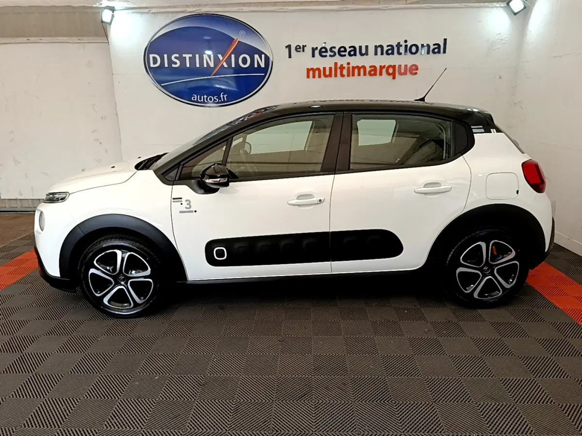 Profil côté gauche d'une Citroën C3 blanche 2019 avec toit noir et protections latérales noires distinctives.