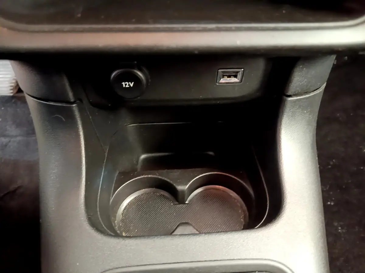 Gros plan sur la console centrale noire de la Citroën C3 avec prise 12V et port USB visibles.