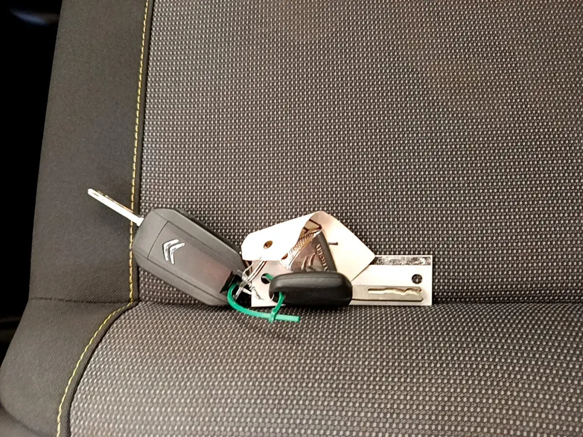 Clé de voiture Citroën posée sur un siège tissu gris avec surpiqûres jaunes, intérieur d'une C3 blanche 2019.