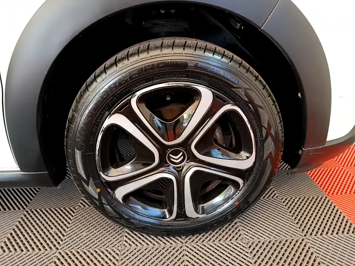 Gros plan sur la roue avant droite noire et chromée de la Citroën C3 blanche 2019 PureTech Graphic