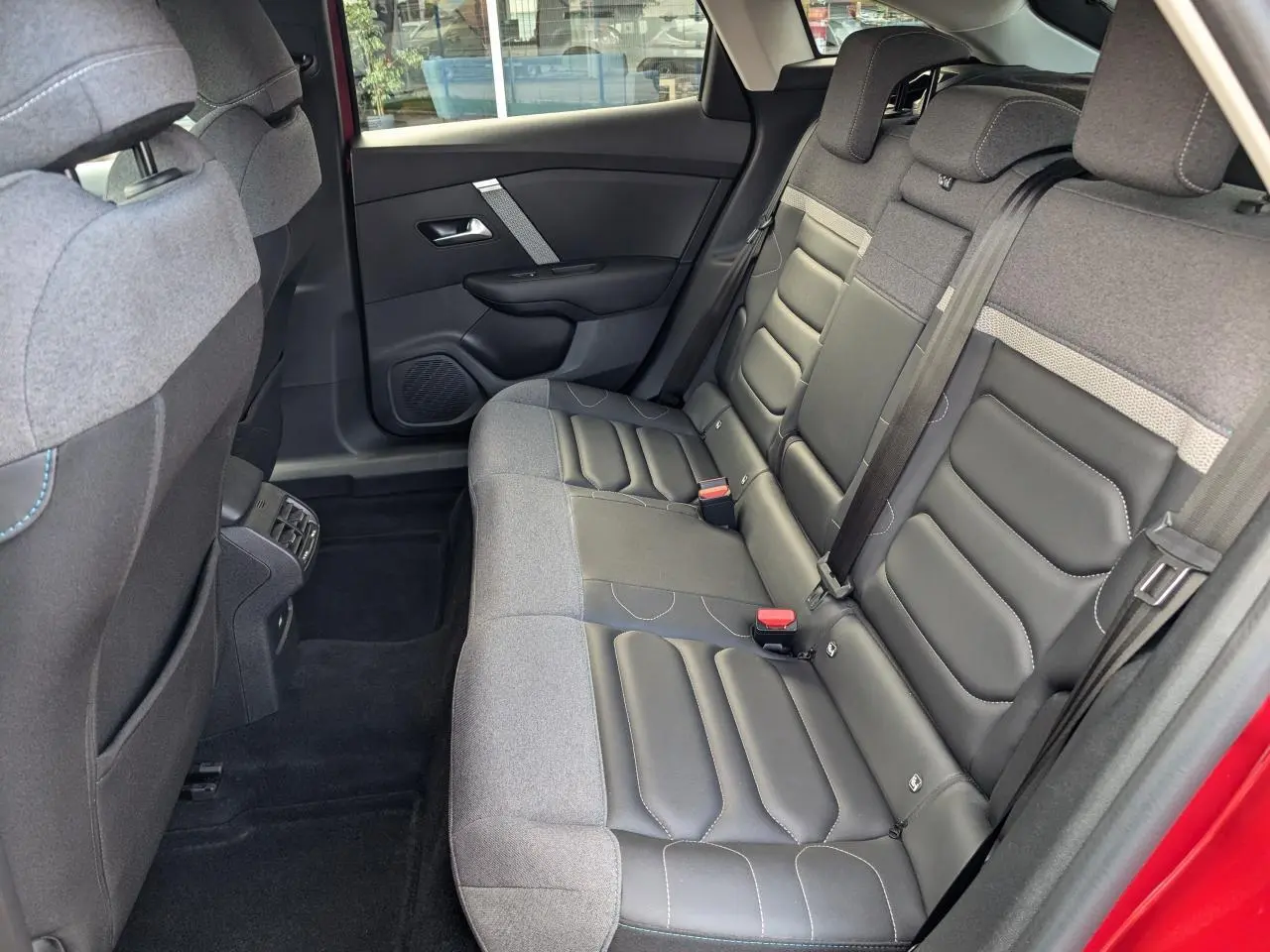 Vue intérieure côté droit de la banquette arrière en tissu gris et cuir noir du Citroën C4 rouge foncé 2024.