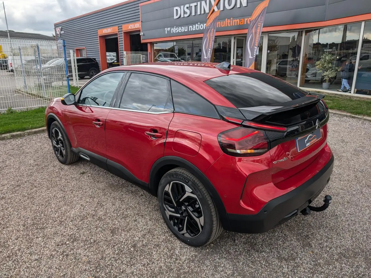 Vue 3/4 arrière droite d'une Citroën C4 rouge foncé avec attelage col de cygne et jantes alliage noires.