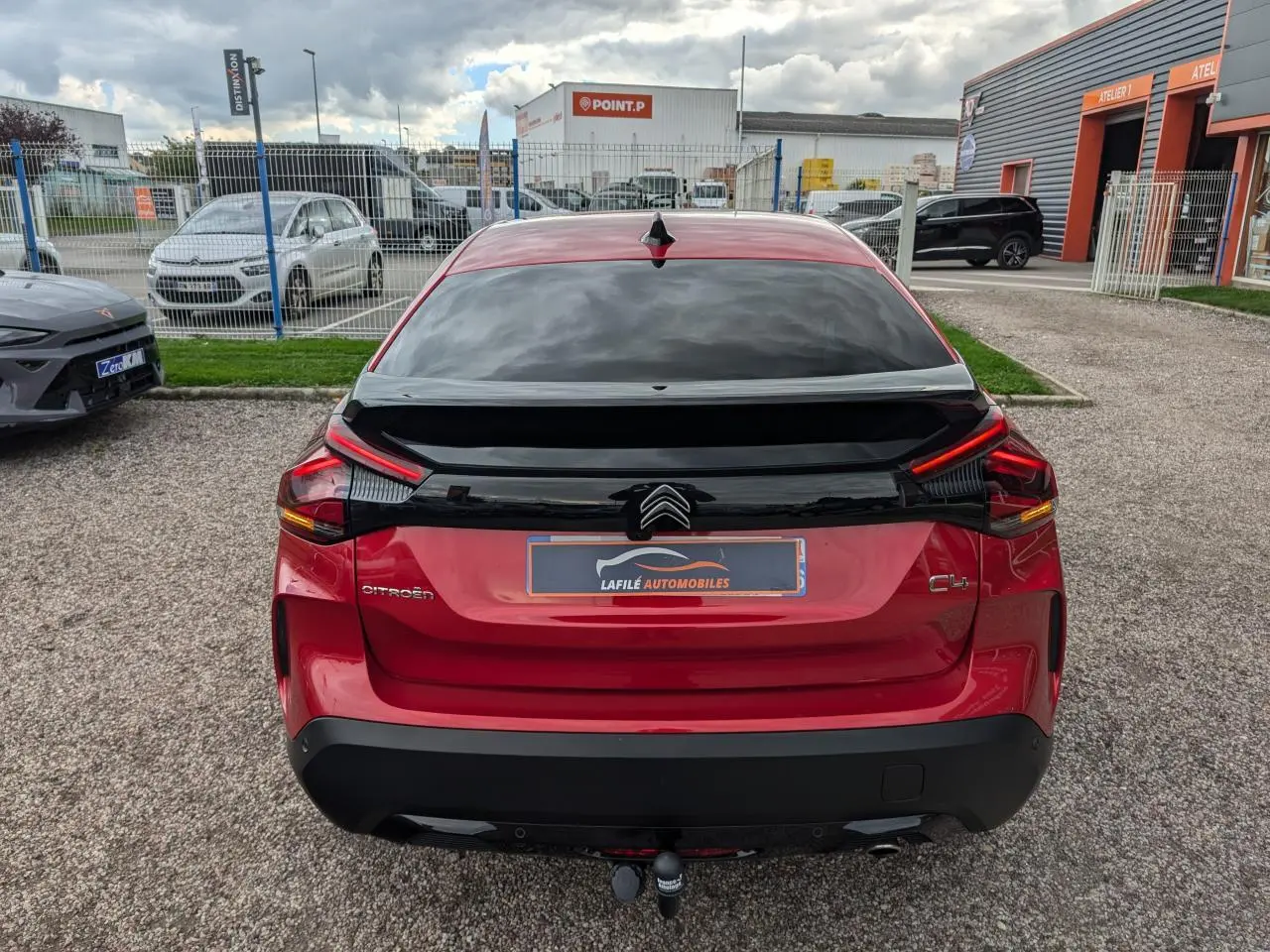 Vue arrière d'une Citroën C4 rouge foncé 2024 avec attelage col de cygne et lunette arrière surteintée.
