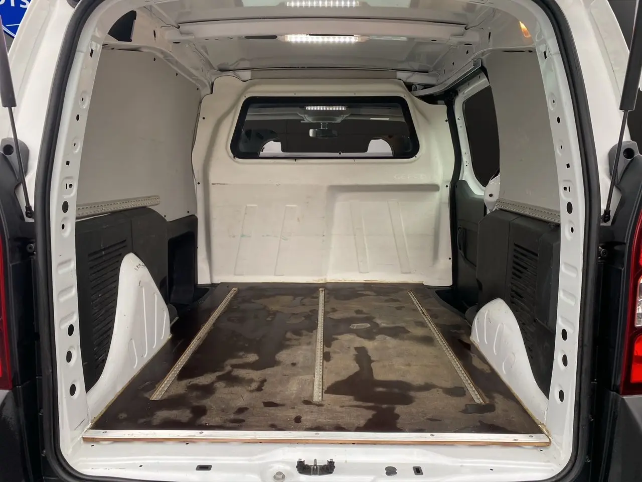 Vue intérieure arrière du Citroën Berlingo blanc 2018, montrant l’espace de chargement vide avec sol usé.