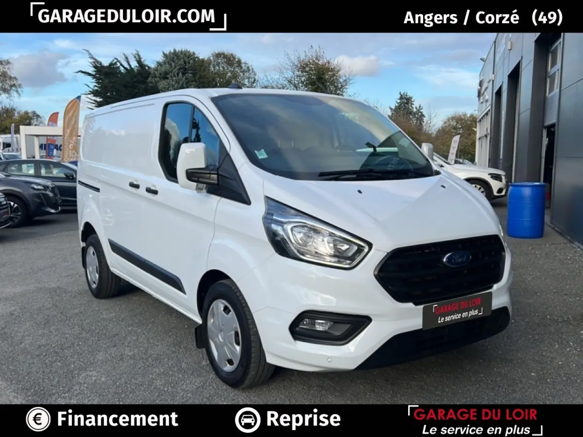 Ford Transit Custom blanc en 3/4 avant droit, fourgon utilitaire avec calandre noire et feux LED visibles.