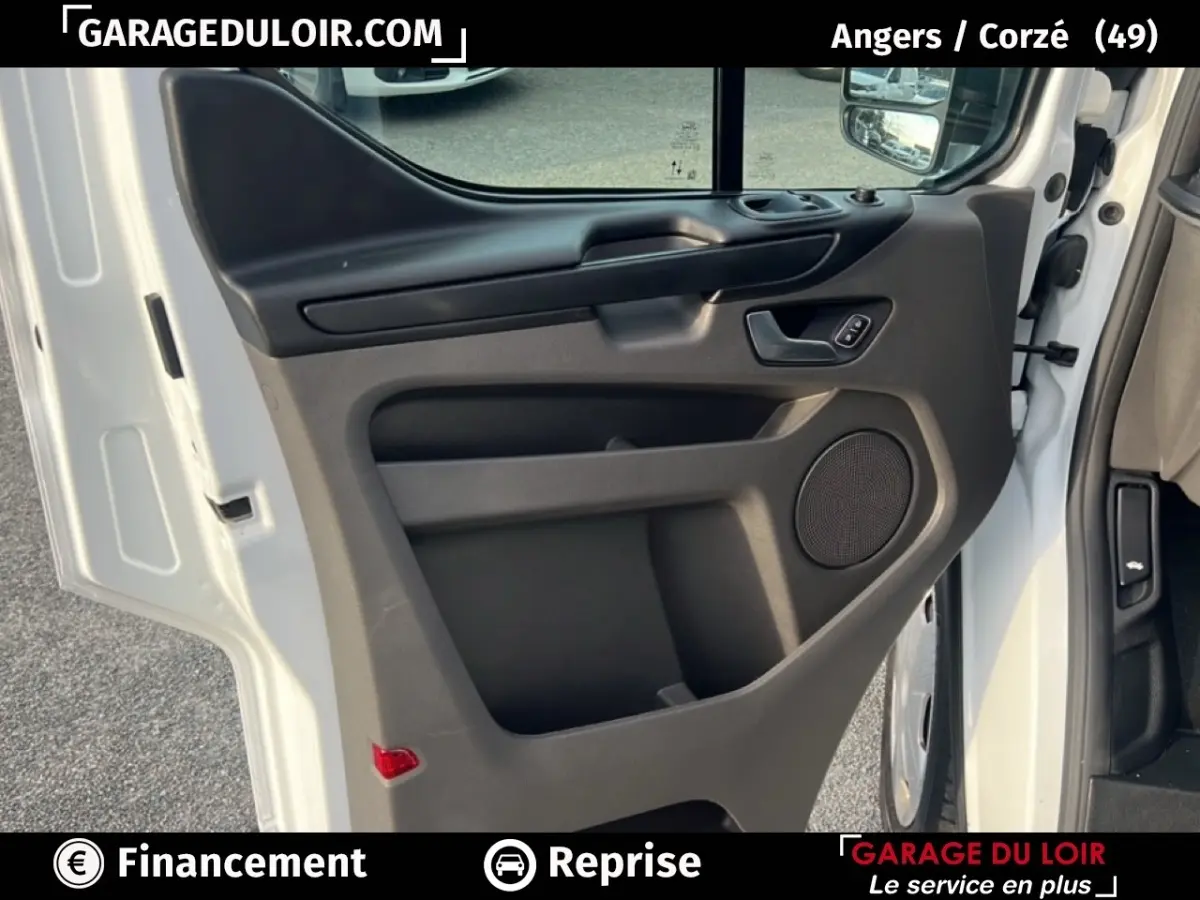 Vue rapprochée de la porte avant gauche blanche du Ford Transit Custom Fourgon 2023, avec panneau noir et haut-parleur intégré.