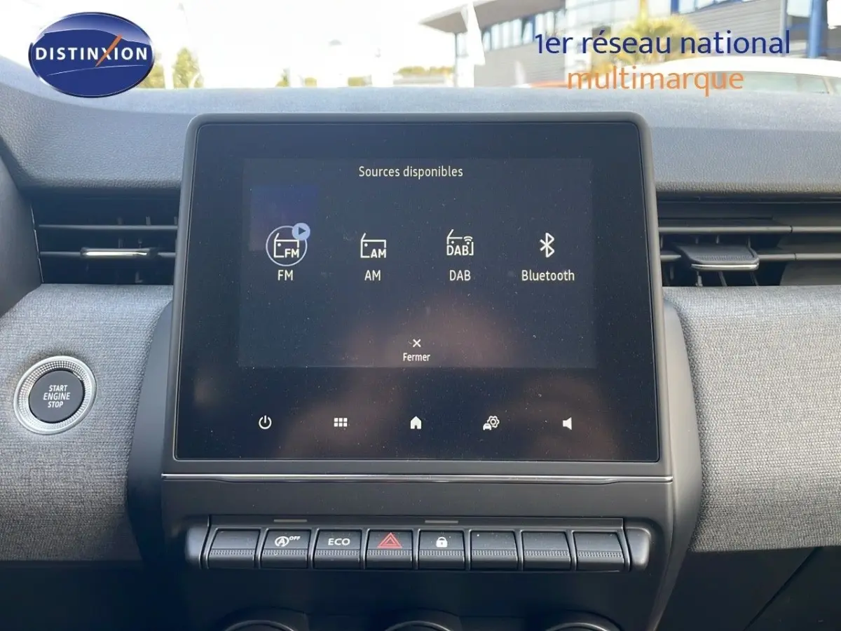 Vue intérieure centrée sur l'écran tactile multimédia de la Renault Clio Evolution Blue dCi 100, avec bouton démarrage à gauche.