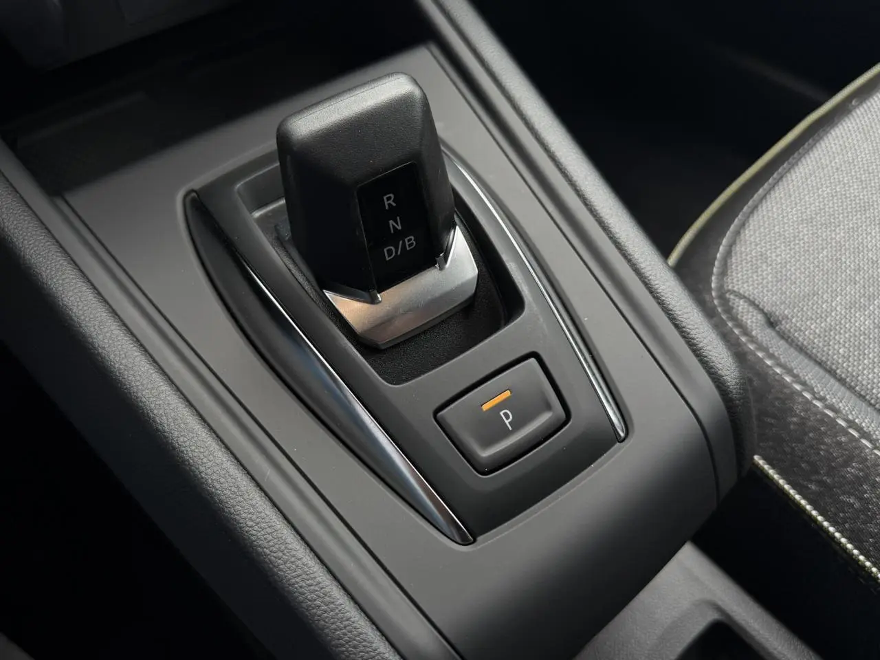 Gros plan sur la commande de boîte automatique noire du Renault Captur gris Rafale, avec bouton de stationnement éclairé.