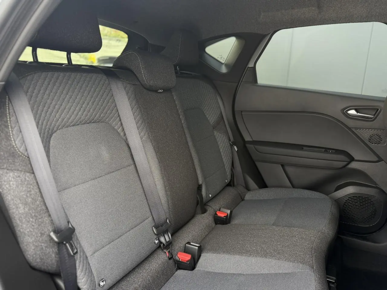 Vue intérieure côté droit des sièges arrière gris foncé du Renault Captur 2026 avec ceinture de sécurité et garnitures tissu.