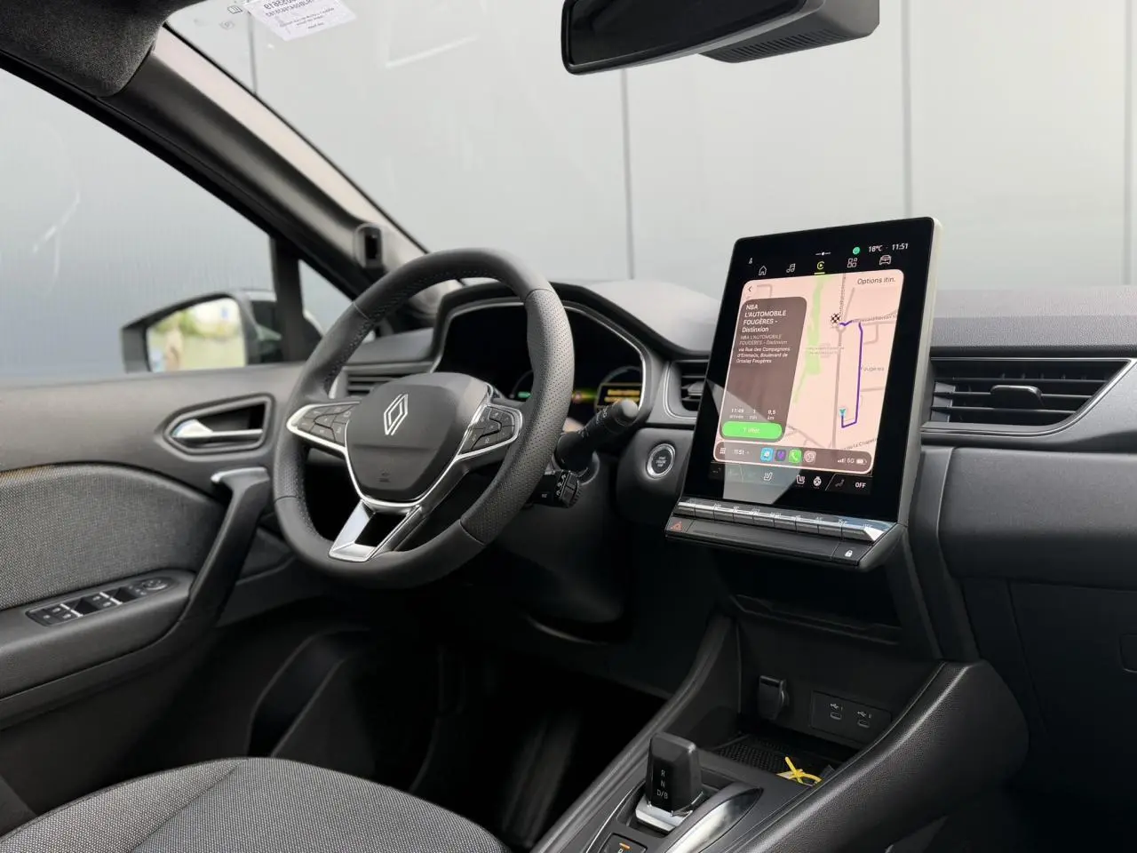 Vue intérieure côté conducteur du Renault Captur 2026, tableau de bord noir avec écran tactile vertical et volant multifonction.