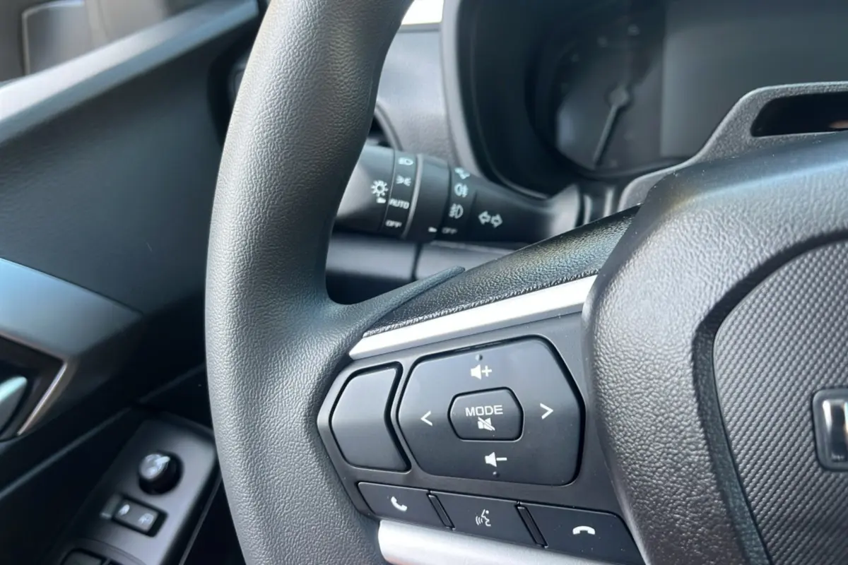 Gros plan sur les commandes multimédia au volant du pick-up Isuzu D-MAX 2026, intérieur noir.