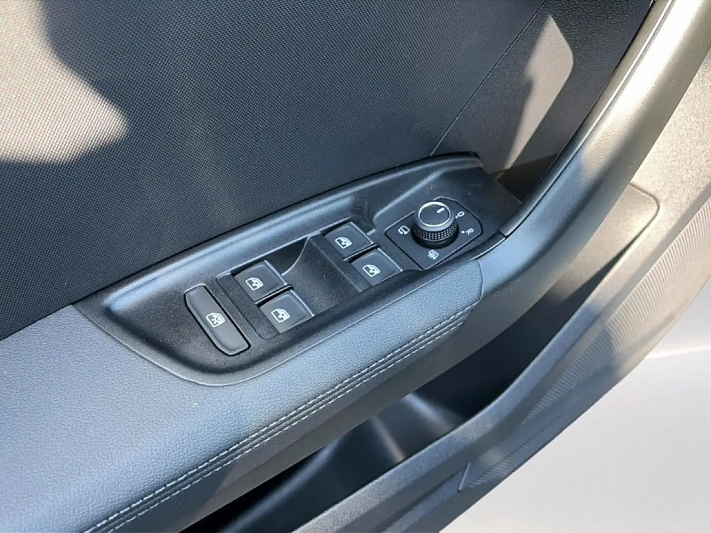 Gros plan sur la commande des vitres électriques et rétroviseurs sur la porte intérieure noire d'une Audi A1 Sportback blanche.