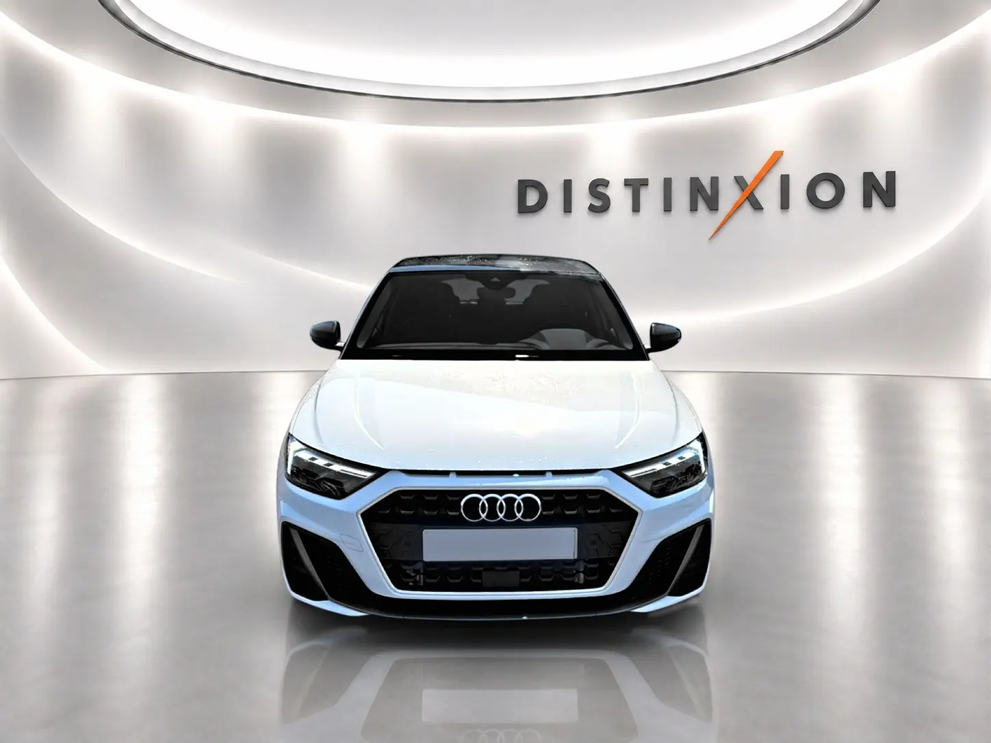Audi A1 Sportback blanc et noir vue de face dans un showroom avec éclairage moderne et logo Distinxion en arrière-plan.