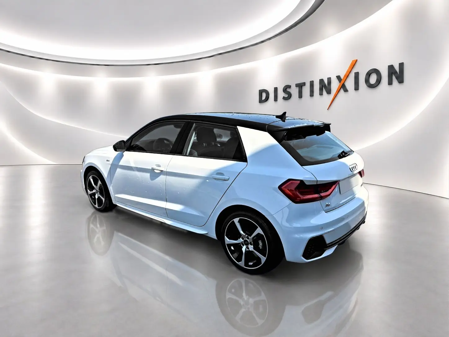 Audi A1 Sportback blanc et noir vue 3/4 arrière droit, avec jantes alu et toit contrasté noir dans showroom lumineux.