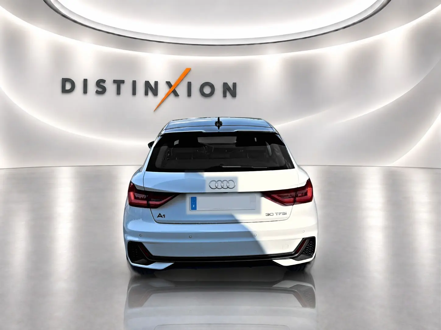 Vue arrière d'une Audi A1 Sportback 30 TFSI blanche avec toit noir, dans un showroom lumineux au logo Distinxion.