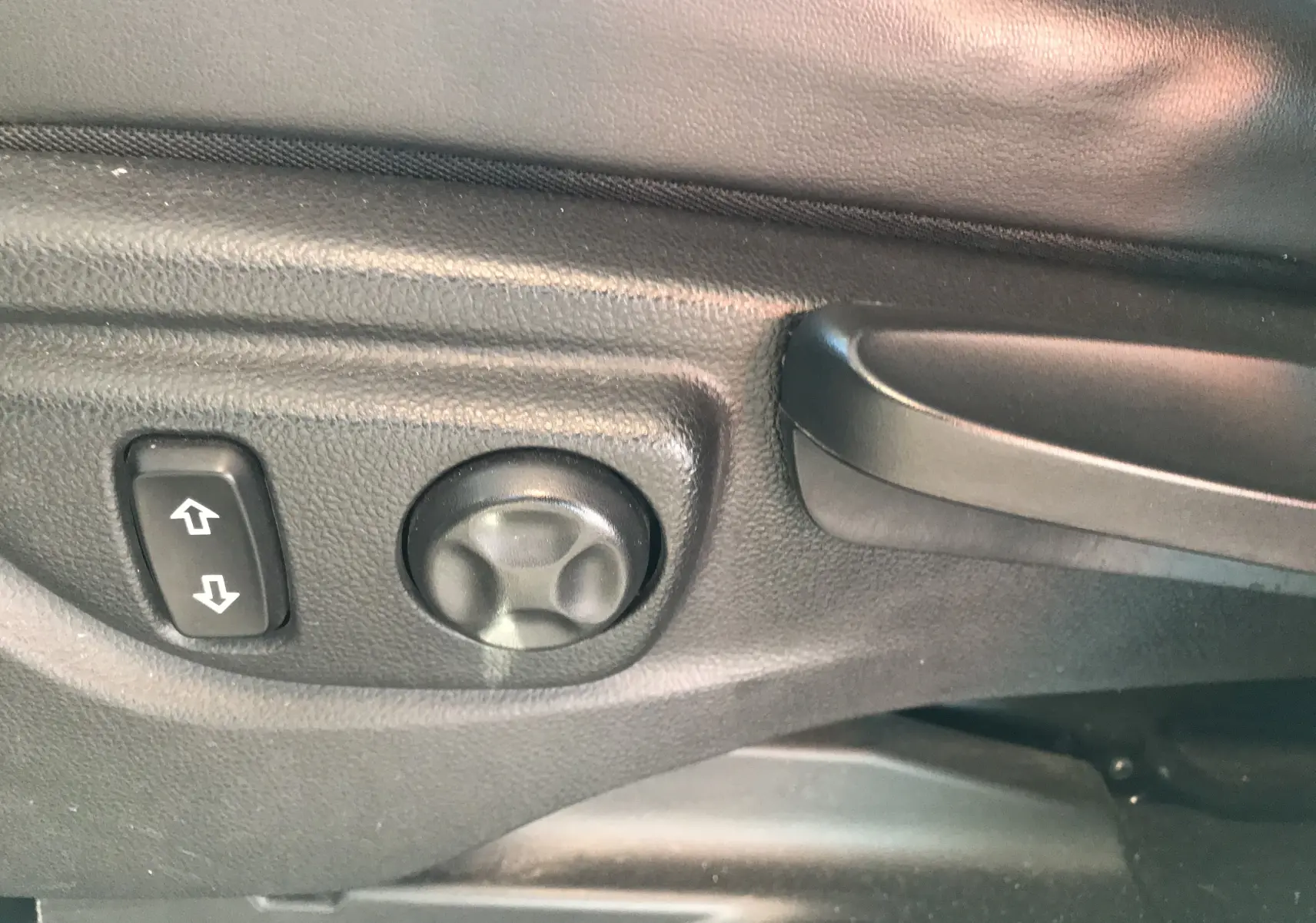 Gros plan sur les commandes de réglage électrique du siège avant gauche d'un Opel Mokka blanc de 2015.