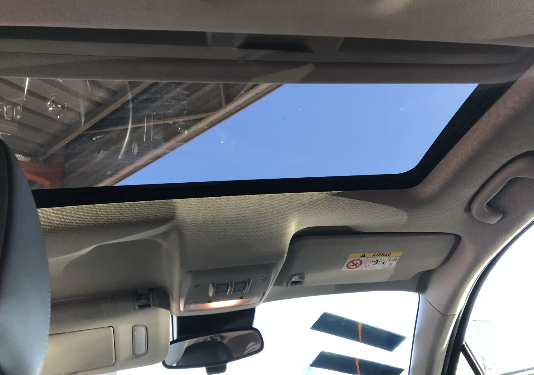 Vue intérieure du toit ouvrant panoramique de l'Opel Mokka blanc, avec pare-soleil et rétroviseur central visibles.